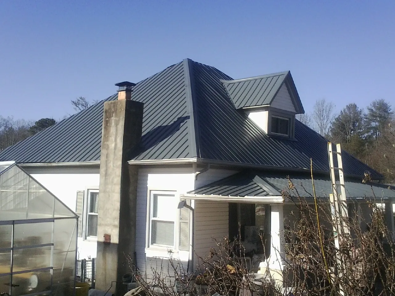 Dark blue standing seam metal roof on a white farmhouse with dormer — Slate & Tile Roof Repair by Roofing Brothers in Gap