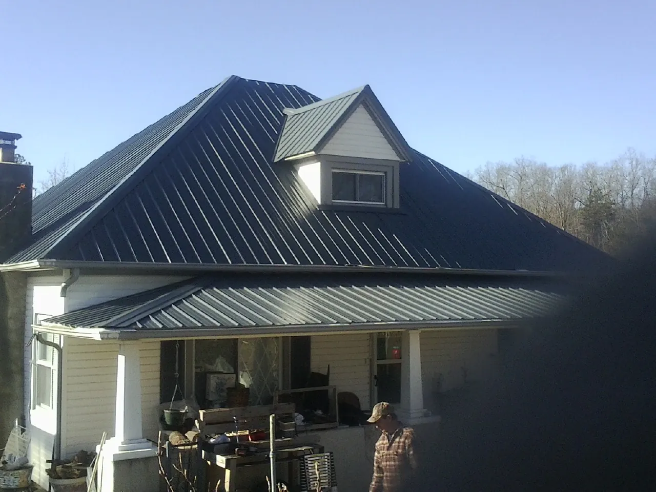Dark blue standing seam metal roof with a dormer above a front porch in Gap