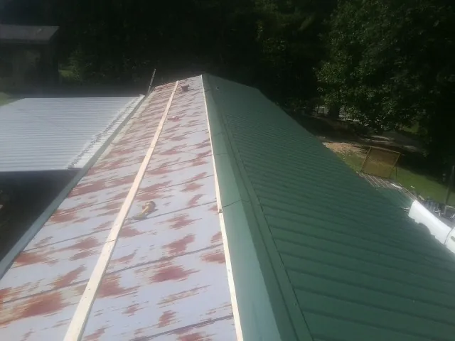 Old rusted panels beside newly installed green metal roofing — Wind Damage Roof Repair by Roofing Brothers in Gap
