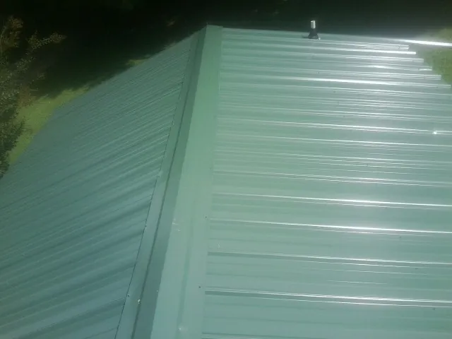New green metal panels meeting at the ridge of a roof — Flat Roof Repair work by our crew in Gap